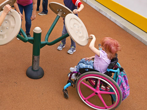Child in a wheelchair using equipment on the Fitness Path.